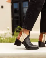 Botines Chelsea de cuero, color negro, con detalles en cuero marrón texturizado (tipo cocodrilo) y paneles laterales en color beige claro. Tienen un taco ancho y cuadrado, y cierre de cremallera lateral en color beige.