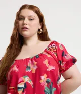 Blusa plus size con mangas cortas abullonadas y elástico en los hombros. Prenda confeccionada en viscolino y estampada con motivos de follajes y tucanes.