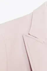 Blazer color rosa pálido de corte entallado y doble botonadura dorada.