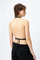 Top halter negro con escote profundo y destellos metalizados. El frunce frontal realza la silueta y el tajo sutil aporta un toque atrevido.