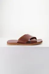 Sandalias planas de cuero color marrón con tiras anchas cruzadas en el empeine.