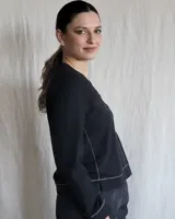 Remera blanca de mangas largas con cuello en V y costuras a la vista.