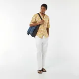 Camisa de manga corta color mostaza con estampado de palmeras en blanco.