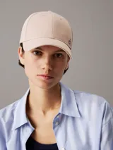 Gorra de béisbol color beige claro, confeccionada en sarga de algodón orgánico, con visera curva y herraje metálico con el monograma 'ck' en el frente.