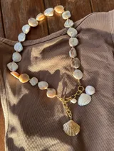 Collar con cuentas de nácar y dijes de conchas marinas doradas.