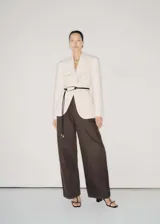 Pantalón de jean acampanado color marrón oscuro, con tiro alto, cinco bolsillos y cierre frontal con cremallera y botón.