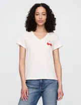 Remera color amarillo claro con cuello en V y estampado de cerezas rojas con moño.
