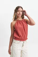 Blusa sin mangas color ladrillo, con cuello halter y elástico en el cuello y la cintura.