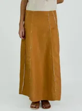 Pollera larga negra de corte amplio, con costuras verticales que simulan pliegues y terminaciones deshilachadas. Se combina con una musculosa negra de escote redondeado.