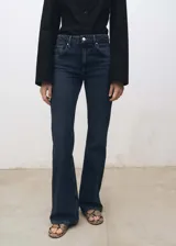 Pantalón de jean azul oscuro, de tiro alto, corte flare y cinco bolsillos.
