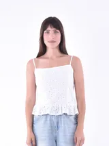 Musculosa blanca de broderie con escote recto y tirantes finos. Presenta un diseño calado con motivos florales y un pequeño volado en el ruedo.