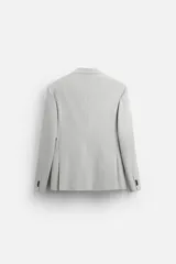 Blazer straight fit color gris claro confeccionado en tejido con viscosa. Tiene cuello con solapas de muesca, manga larga acabada en puño con botón, bolsillo de vivo en pecho, bolsillos de plastrón en cadera y bajo con aberturas en espalda. Cierre frontal de botonadura.