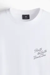 Remera blanca de algodón con cuello redondo y hombros caídos. Estampado pequeño en el pecho con la frase "Puerto Vallarta Beach Bar". Corte holgado.