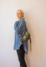 Bandolera negra con estampado dorado, confeccionada en cuero y con correa regulable.