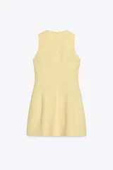 Vestido corto color amarillo pastel, de cuello redondo y sin mangas. Presenta pliegues con volumen en el ruedo y cierre trasero con cremallera oculta.