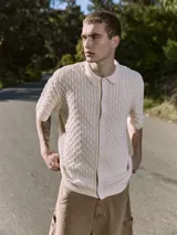 Polo de hombre color crema, tejido de punto cable, con cuello tipo polo, manga corta y cierre con botones.