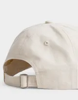 Gorra de gabardina color crudo con visera curva y detalle de roturas. Bordado frontal con la palabra "Weekend" en negro.