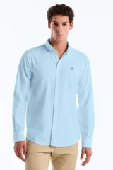 Camisa de manga larga color celeste claro, con cuello abotonado (button-down) y pequeño logo de pingüino bordado en el pecho.