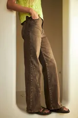 Pantalón de jean color marrón con efecto lavado, corte Oxford de pierna ancha y tiro medio alto. Presenta aberturas en el ruedo.