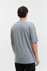 Remera gris con efecto gastado, corte oversize, manga corta y cuello redondo. Estampa frontal con la palabra "Mistr" y logo de la marca en azul.
