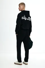 Pantalón tipo jogger negro, de corte recto y silueta clásica, confeccionado en tejido de punto de mezcla de algodón. Presenta pliegue cosido frontal, cintura elástica con cordón ajustable y bolsillos laterales y trasero insertado.