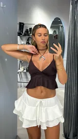 Minifalda blanca de tiro bajo con volados y lazo ajustable en la cintura.