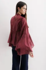 Camisa color marrón con cuello mao, mangas largas abullonadas y detalle de volados en el frente.