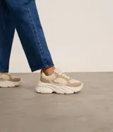 Championes urbanos color beige con detalles en cuero sintético y gamuza. Presentan cordones blancos, suela chunky y recortes contrastantes.