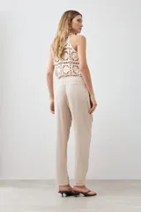Pantalón de lino color beige con cintura elastizada con cordón ajustable, corte recto y pespuntes verticales al frente.