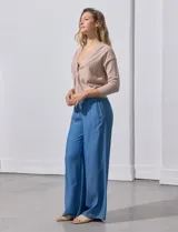 Cárdigan color beige tejido en hilado fino, con escote en V y cierre frontal con un botón.