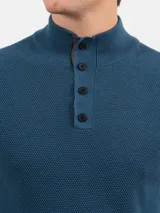 Remera de punto color azul petróleo, con cuello alto abotonado.