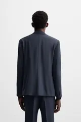 Blazer azul marino de corte recto confeccionado en tejido con lana. Tiene cuello con solapas de muesca, manga larga con puños abotonados, bolsillo de vivo en el pecho, bolsillos de solapa en la cadera, bolsillo interior y cierre frontal con botones.