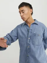 Sobrecamisa de jean celeste con manga larga, cuello clásico, cierre con botones y bolsillo frontal.