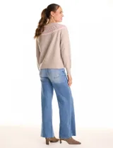 Buzo de punto color beige, con cuello a la base y silueta clásica de hombros relajados. Presenta una guarda tejida con motivos geométricos en tonos rosados, blancos y grises en el canesú. Puños y ruedo con acabado acanalado.