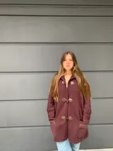 Saco capa bordo de lana con cierre de broches tipo duffle coat y mangas anchas con detalle de tejido trenzado.