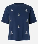 Remera azul marino de algodón con cuello redondo y mangas cortas. Presenta un estampado de barcos de vela blancos.