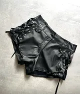 Short negro de cuerina, tiro alto, con trenzado lateral y tachas plateadas.