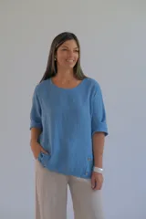 Blusa celeste de lino con mangas 3/4 con botón y cuello redondo.