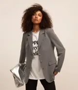 Blazer gris de poliéster, viscosa y elastano, de corte alargado, con cuello con solapas, bolsillos y cierre frontal con botones.