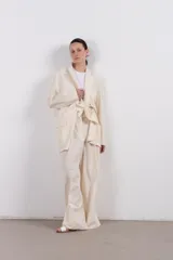 Blazer color crema de corte amplio con diseño asimétrico y detalle de nudo frontal.