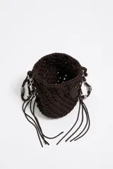 Bolso marrón tipo bucket, tejido con cordones gruesos, con asa corta y cierre ajustable con cordón. Incluye etiqueta logotipada BIMBA Y LOLA y charms metálicos plateados.