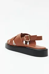 Sandalias negras de símil cuero con agarre ajustable en el talón y capellada entrelazada. Plataforma de 3 cm de alto.