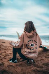 Buzo hoodie marrón con estampado en la espalda de una flor con un ojo en el centro y texto en la parte inferior.