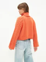 Sweater tejido color naranja oscuro, con cuello alto y mangas largas acampanadas.