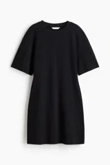 Vestido corto negro de punto de algodón suave con cuello redondo ribeteado acanalado, hombros caídos y mangas al codo. Pinzas moldeadoras en la parte posterior de la cintura para estilizar la figura.