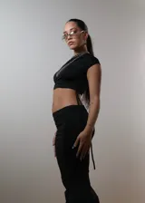 Conjunto de top corto negro de un solo hombro y falda larga negra con cordones laterales.