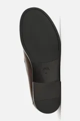 Mocasín de vestir color marrón oscuro, con detalle de borlas en la parte delantera.