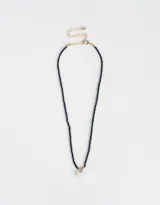 Collar corto de mostacillas azul marino con dije de corazón blanco y detalles dorados.
