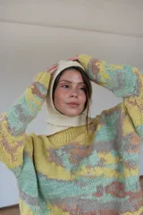 Capucha tejida a mano en lana merino color crema, con forma envolvente que cubre la cabeza y el cuello, y lazos tejidos para ajustar bajo el cuello.