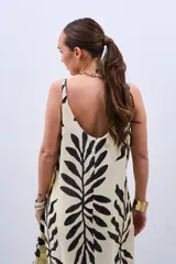 Vestido largo color crudo con estampado de hojas negras, de corte suelto y breteles finos.